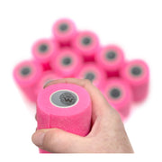 Hand holding 1 of 12 rolls of WildCow 4 Inch Neon Pink Vet Wrap