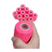 Hand holding 1 of 12 rolls of WildCow 4 Inch Neon Pink Vet Wrap