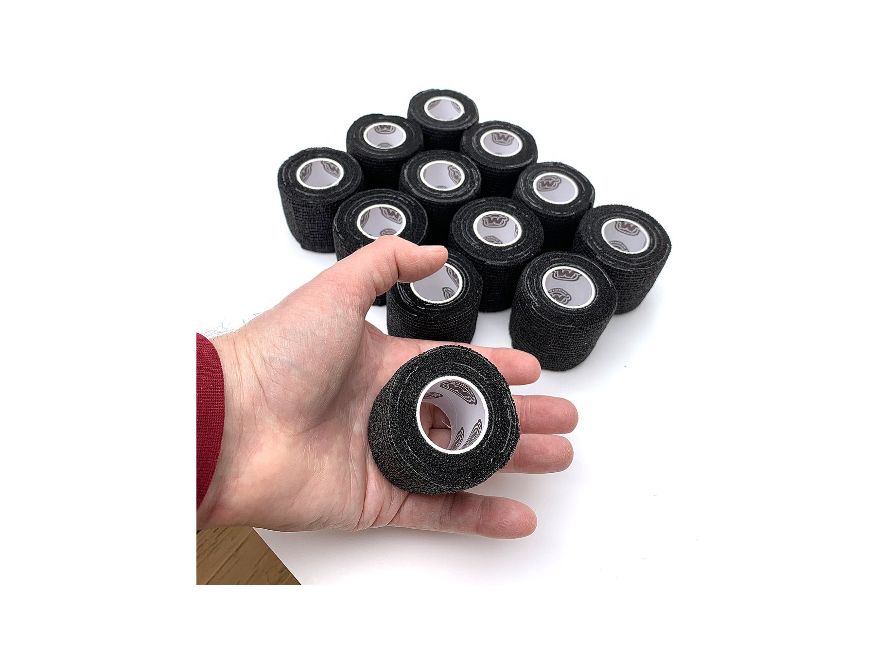 Hand Holding 1 of 12 Rolls of WildCow 2 Inch Black Vet Wrap